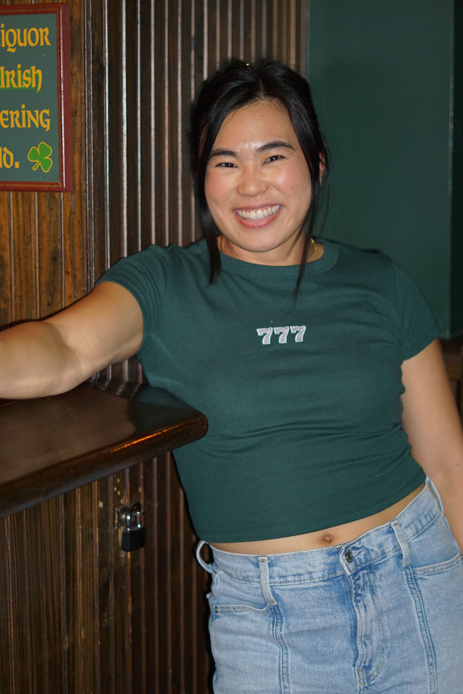 Woman wearing a fitted baby tee embroidered with the number 777.