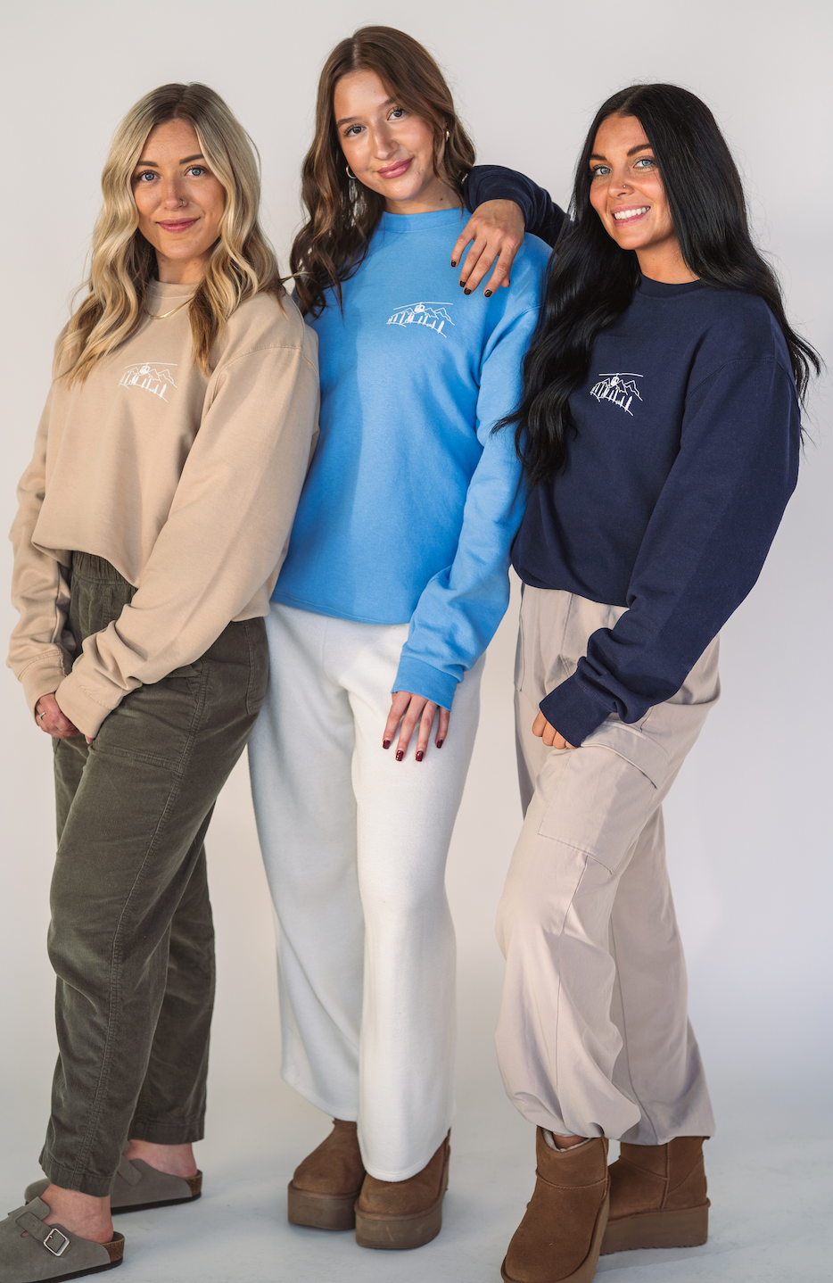 Models wearing the Alpine Inspired embroidered crewneck styled with casual winter layers.