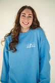 Model wearing close-up of the embroidered Alpine Inspired artwork on a crewneck sweatshirt.