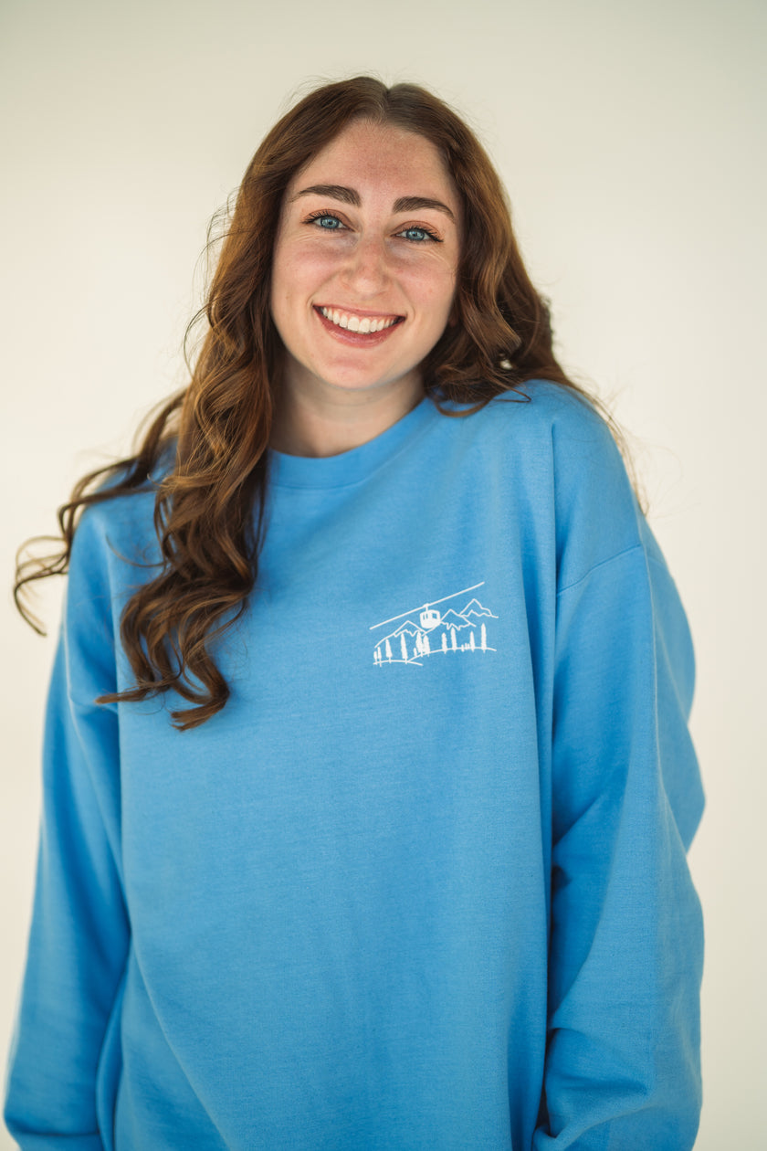 Model wearing close-up of the embroidered Alpine Inspired artwork on a crewneck sweatshirt.