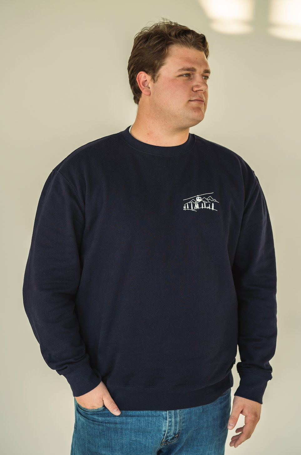 Model wearing the Alpine Inspired embroidered crewneck styled with casual winter layers.