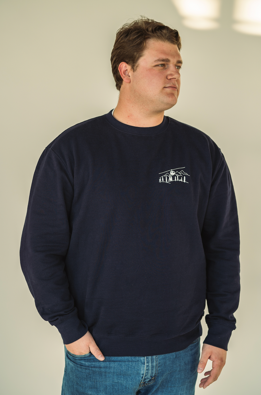 Model wearing the Alpine Inspired embroidered crewneck styled with casual winter layers.