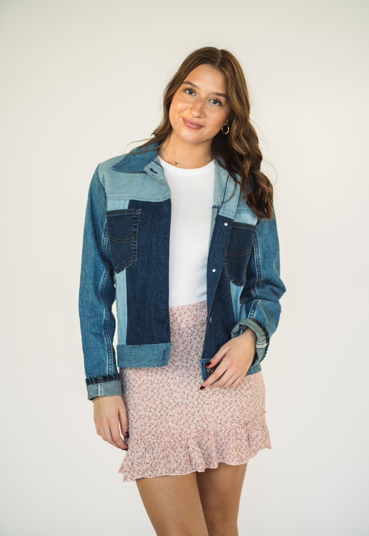 Model wearing a one-of-a-kind patchwork denim jacket made from recycled jeans with contrasting light and dark wash denim panels.