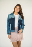 Model wearing a one-of-a-kind patchwork denim jacket made from recycled jeans with contrasting light and dark wash denim panels.