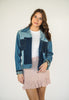 Model wearing a one-of-a-kind patchwork denim jacket made from recycled jeans with contrasting light and dark wash denim panels.