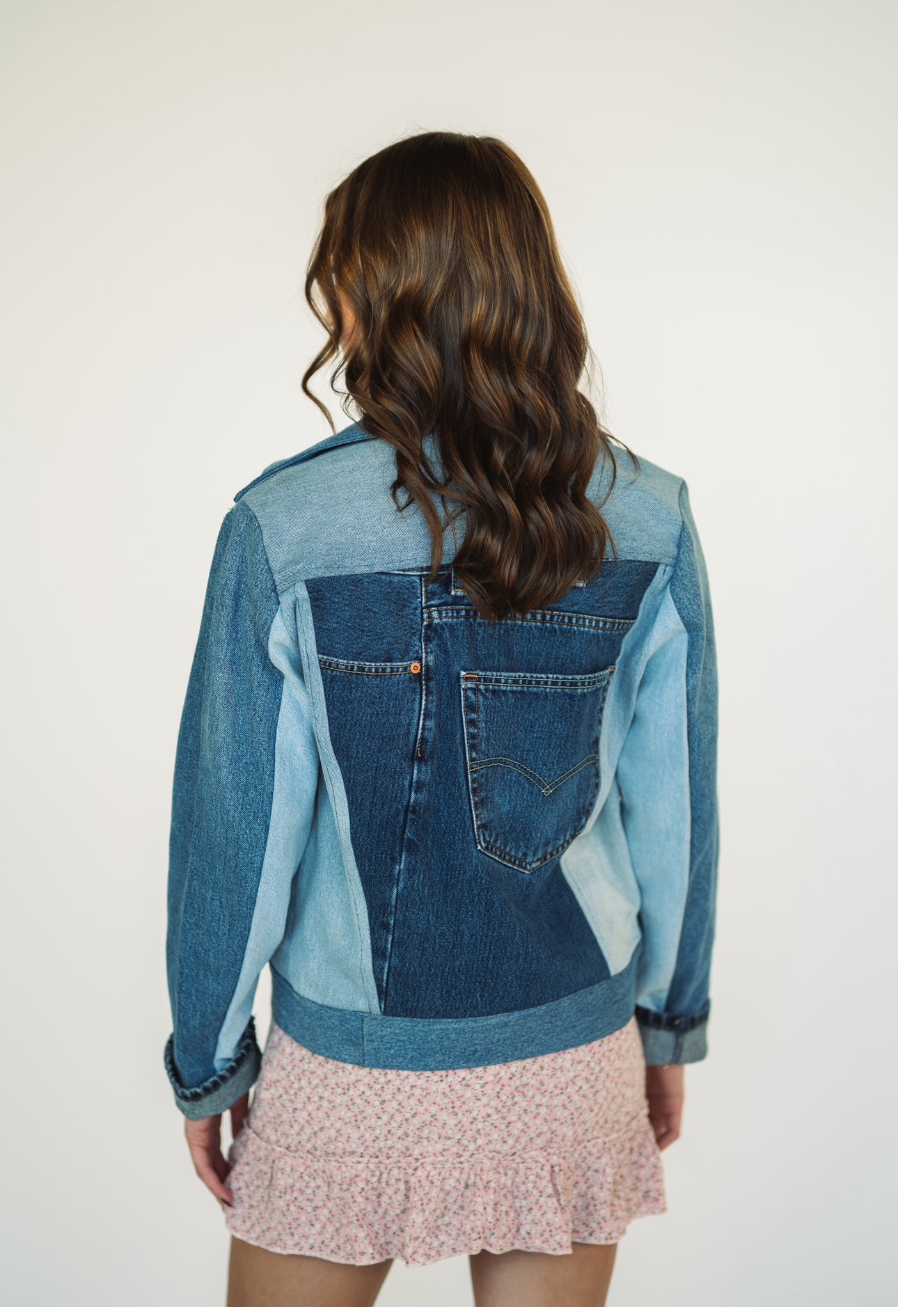 Back view of a one-of-a-kind patchwork denim jacket made from recycled jeans featuring authentic vintage back pocket details.