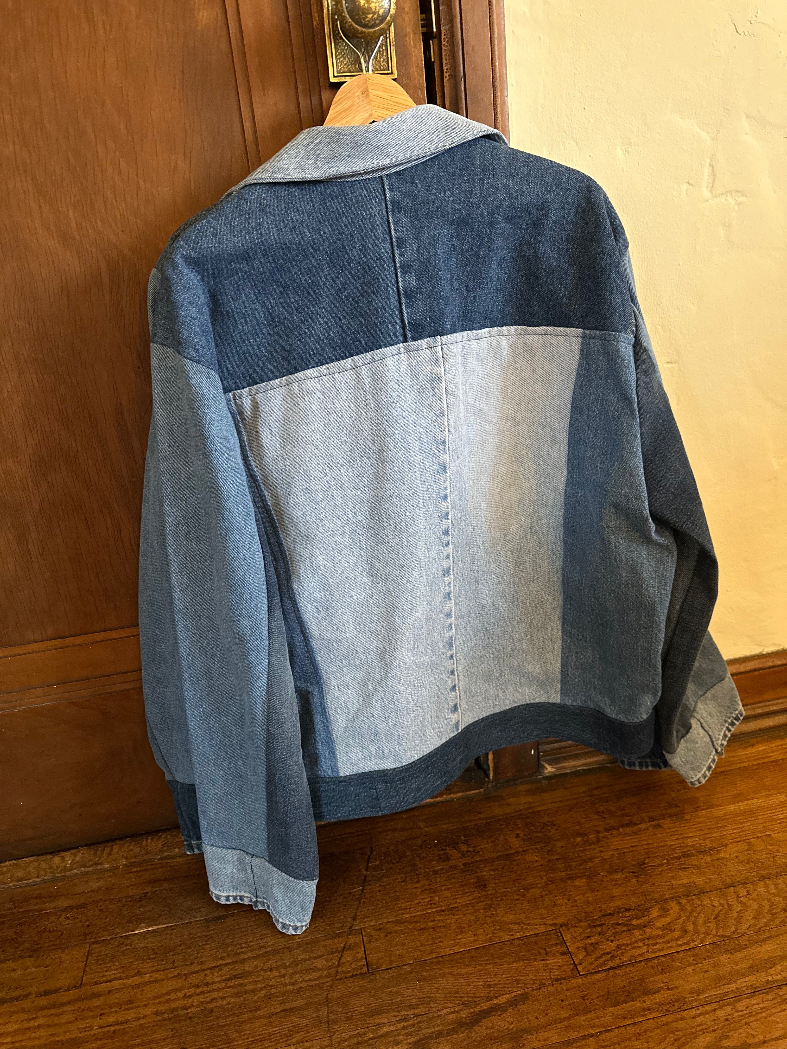 Back view of a one-of-a-kind patchwork denim jacket made from recycled jeans featuring contrasting light and dark wash denim panels, a minimalist color-block design, and a structured collar.