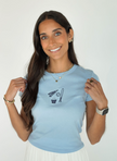 Woman wearing a light blue baby tee embroidered with a CBUS pennant, baseball bat, baseball, and popcorn design.