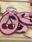 Embroidered cherry keychain with durable metal key ring.