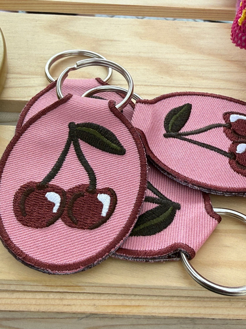 Embroidered cherry keychain with durable metal key ring.