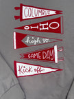 Close-up of a gray T-shirt featuring a graphic of five red and white pennants with text reading 'COLUMBUS', 'OHIO', 'high st.', 'GAME DAY', and 'Kick off'.
