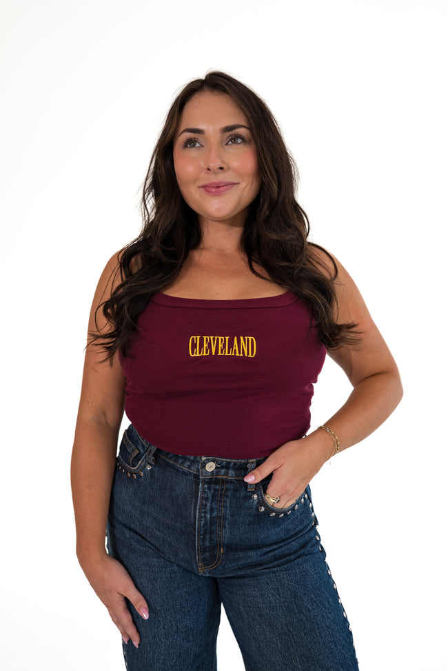 Close-up of a person wearing a maroon ribbed scoop-neck tank top featuring yellow-gold embroidered 