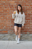 Cream crewneck sweatshirt featuring embroidered coffee icons including an espresso cup, coffee bag, iced coffee, moka pot, and coffee mug.