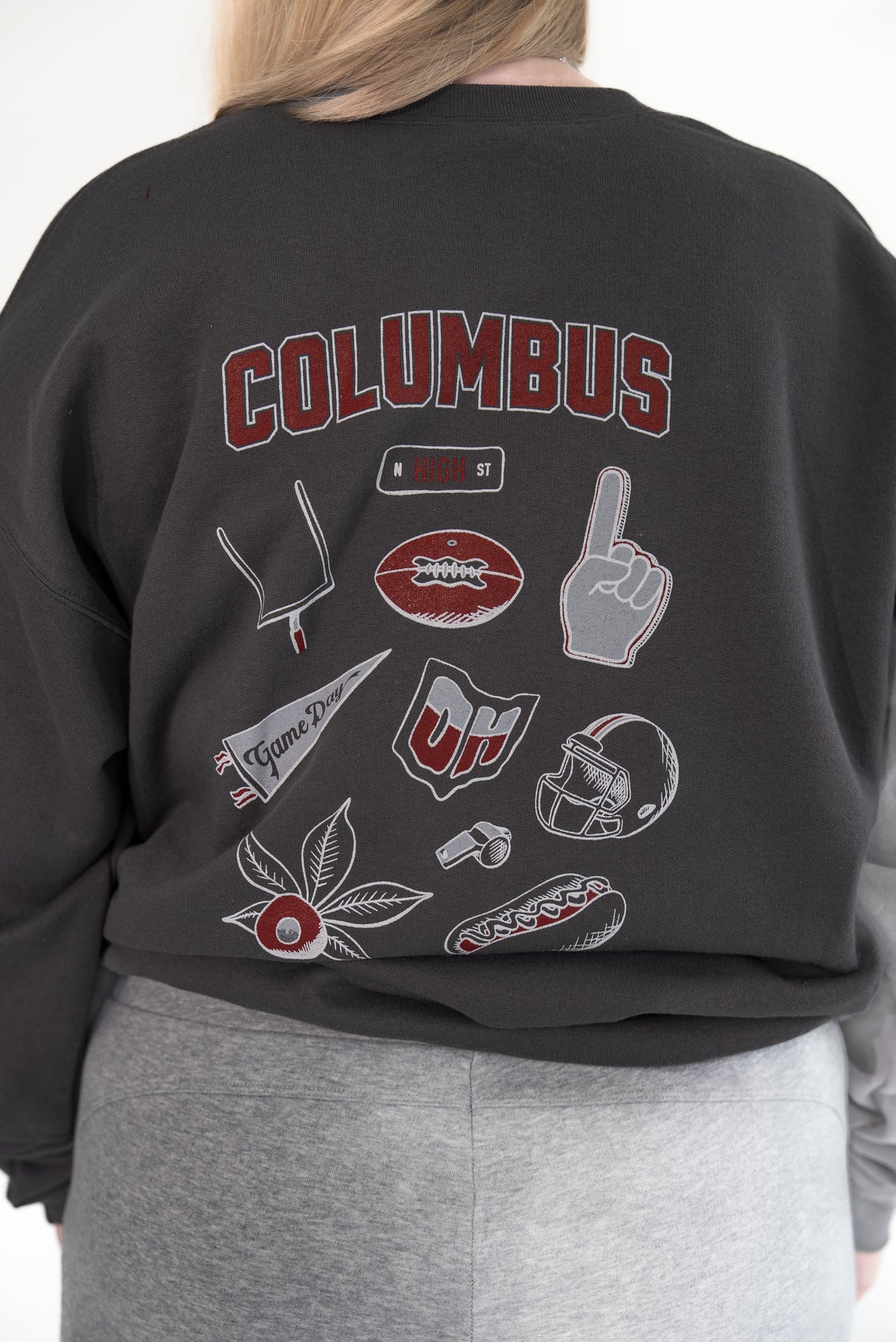 Close-up of the back of a person wearing a charcoal gray crewneck sweatshirt featuring large 