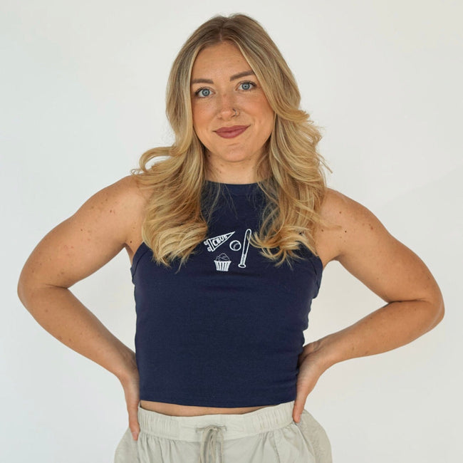 Woman wearing a navy embroidered Columbus hockey tank top featuring a CBUS pennant, hockey stick, puck, and popcorn design.