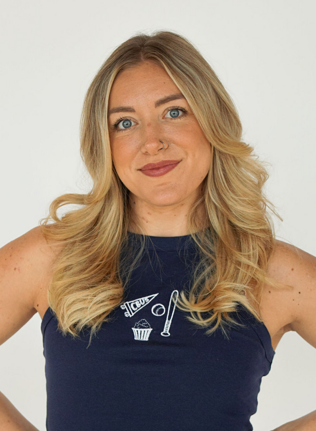 Close-up of model wearing a navy Columbus hockey tank embroidered with a minimalist game day design including a CBUS pennant, hockey stick, puck, and popcorn.