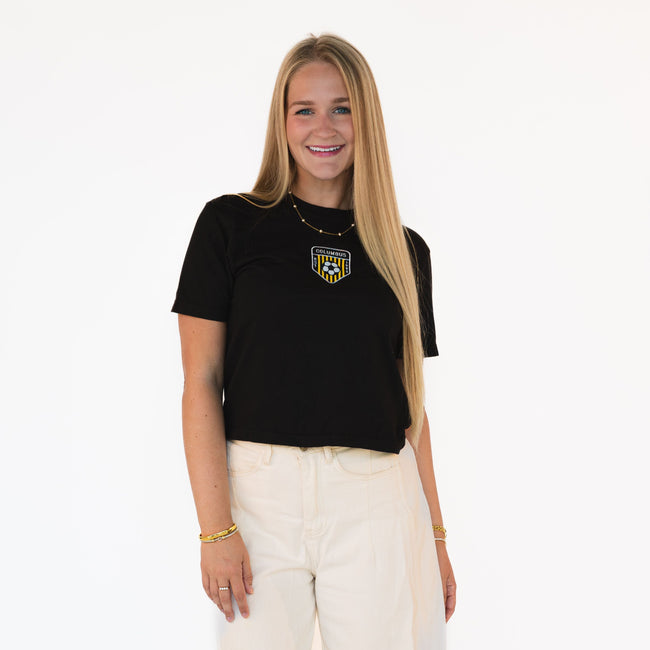 Model wearing a black Columbus Soccer boxy tee with an embroidered vintage-inspired Columbus soccer crest and white denim.