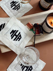 Personalized white linen cocktail napkins featuring a custom embroidered monogram for home entertaining and gifting.