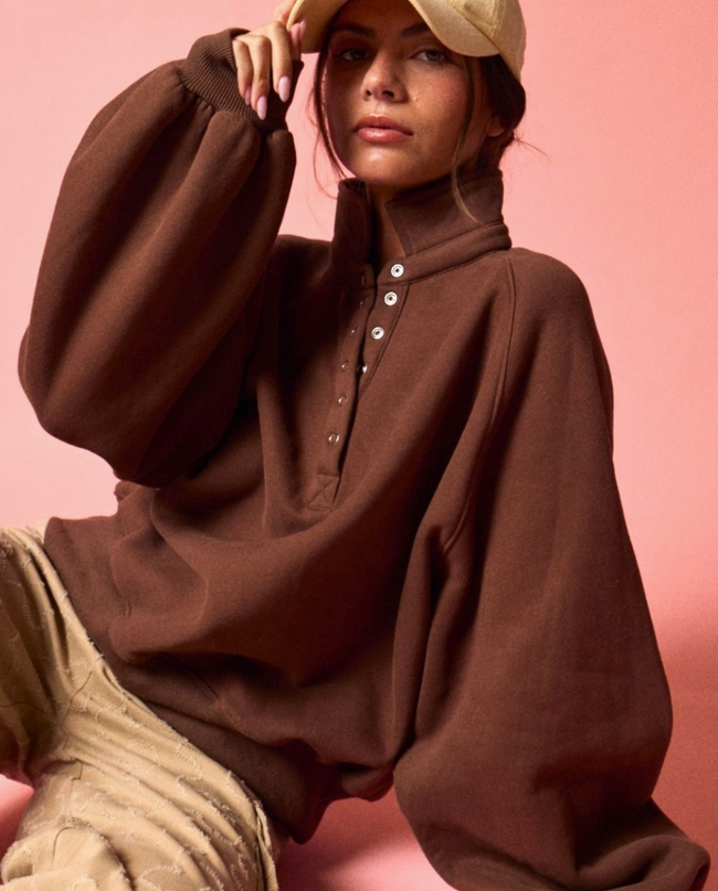 Model wearing a chocolate brown quarter-zip pullover sweatshirt with a high collar and button placket, shown as the blank base garment for the Dancing Buckeyes embroidery design.