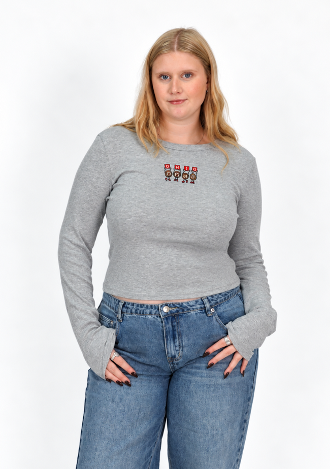 Woman wearing a gray fitted long-sleeve shirt featuring embroidered Dancing Buckeyes spelling “OHIO” across the chest, paired with blue jeans.