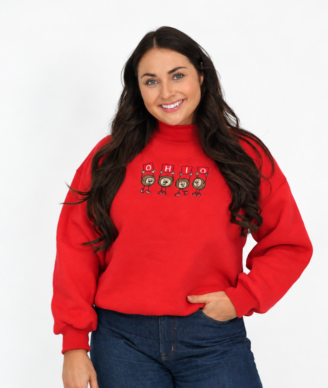 Woman wearing a red mockneck sweatshirt featuring four embroidered Dancing Buckeyes spelling “OHIO,” paired with blue jeans.