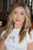 Model wearing the white Tini graphic t-shirt with green embroidery.