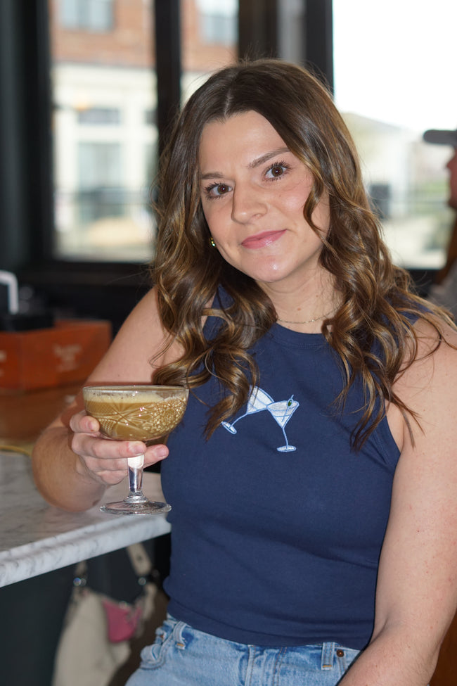 Model wearing the navy Tini Tank with embroidered martini glass design while holding an espresso martini.
