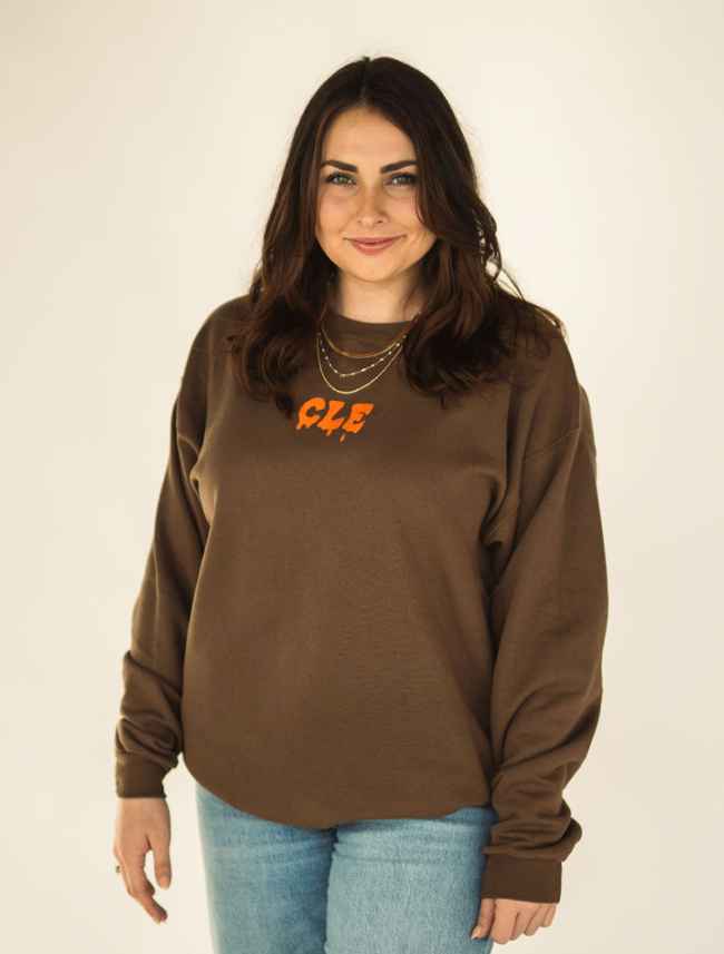Model wearing the brown Drip CLE embroidered sweatshirt styled casually.