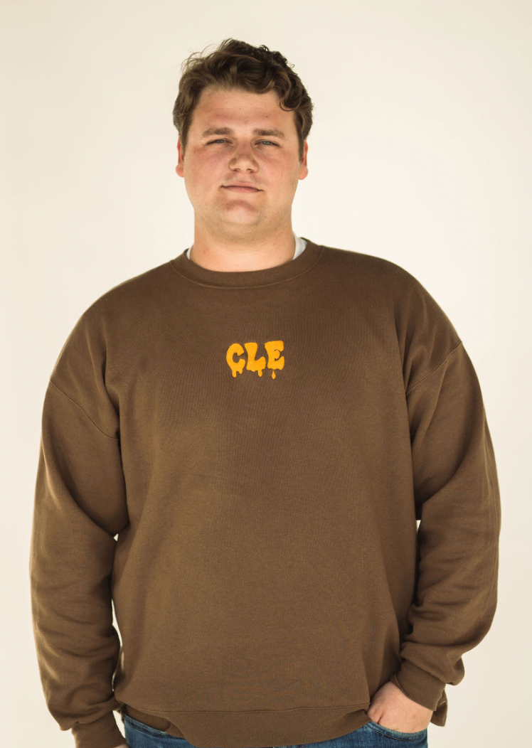 Model wearing the brown Drip CLE embroidered sweatshirt styled casually.