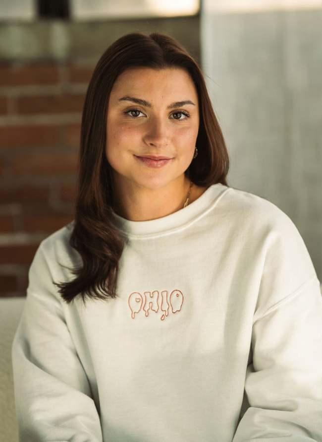 White crewneck sweatshirt with subtle embroidered Drip graphic centered on the chest.