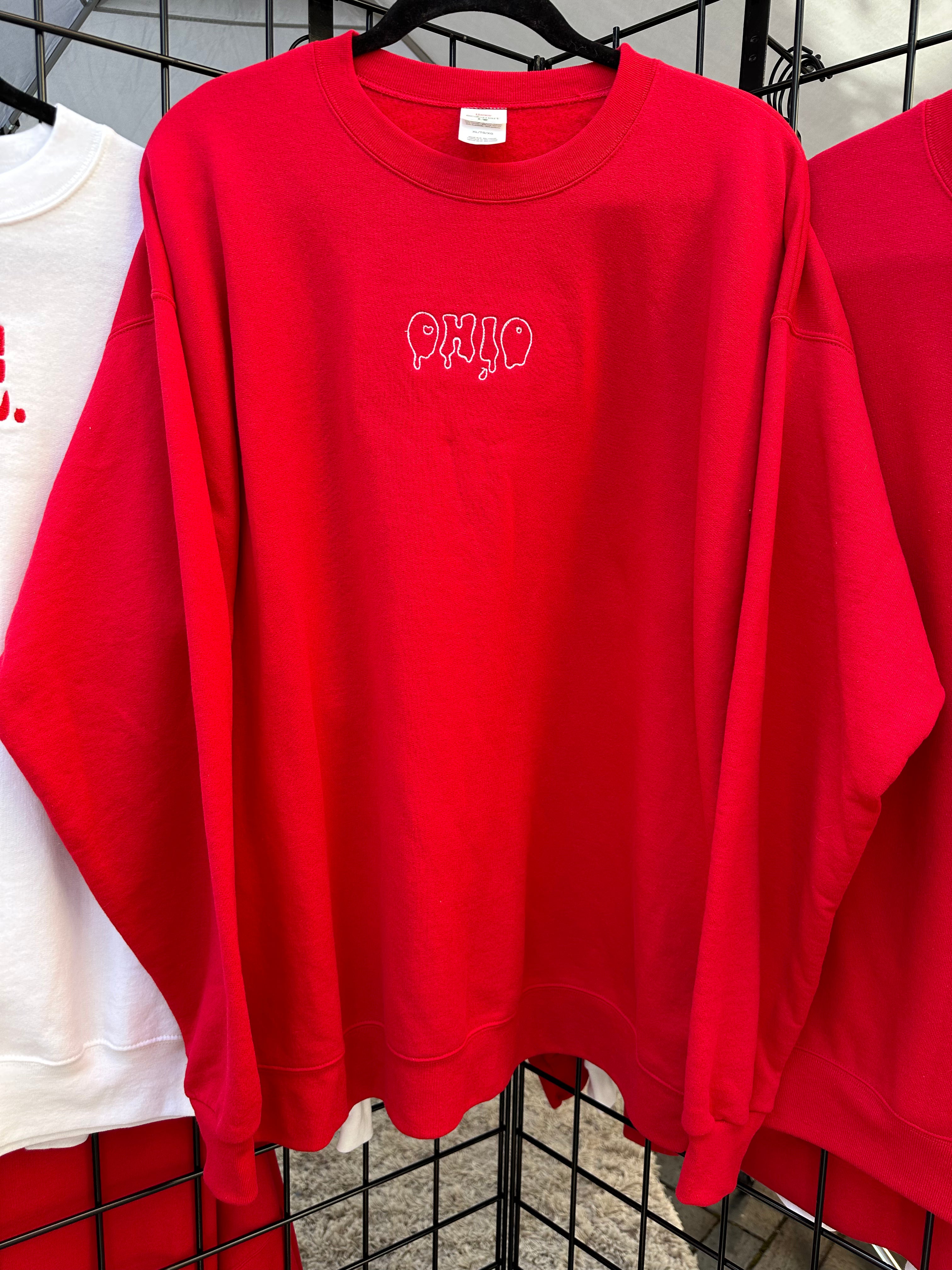 Red crewneck sweatshirt embroidered with the Capsule Collective Ohio Stamp design on the chest.