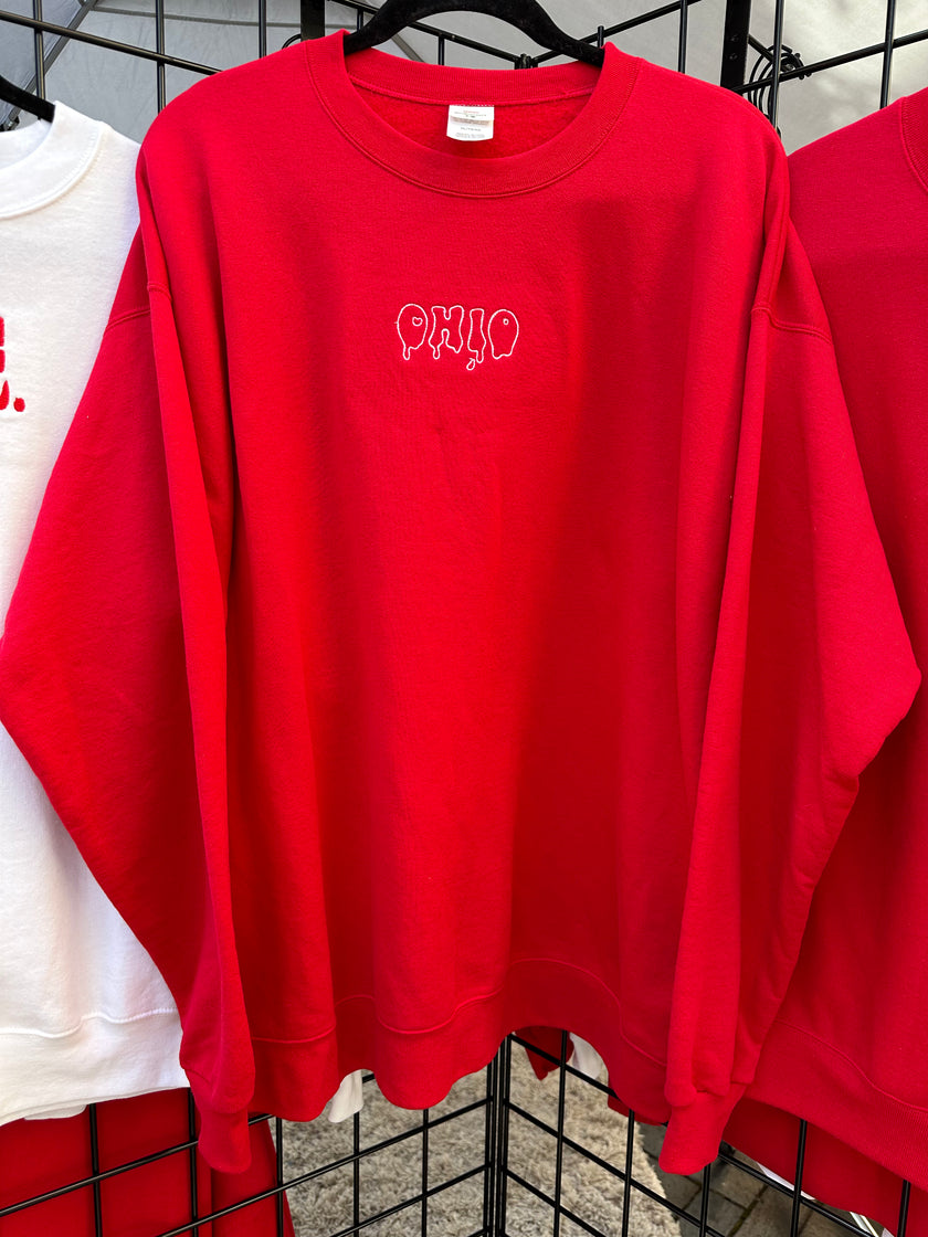 Red crewneck sweatshirt embroidered with the Capsule Collective Ohio Stamp design on the chest.