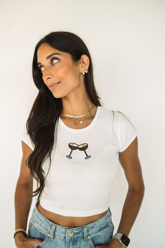 Model wearing a white embroidered espresso martini baby tee featuring a minimalist cocktail design.