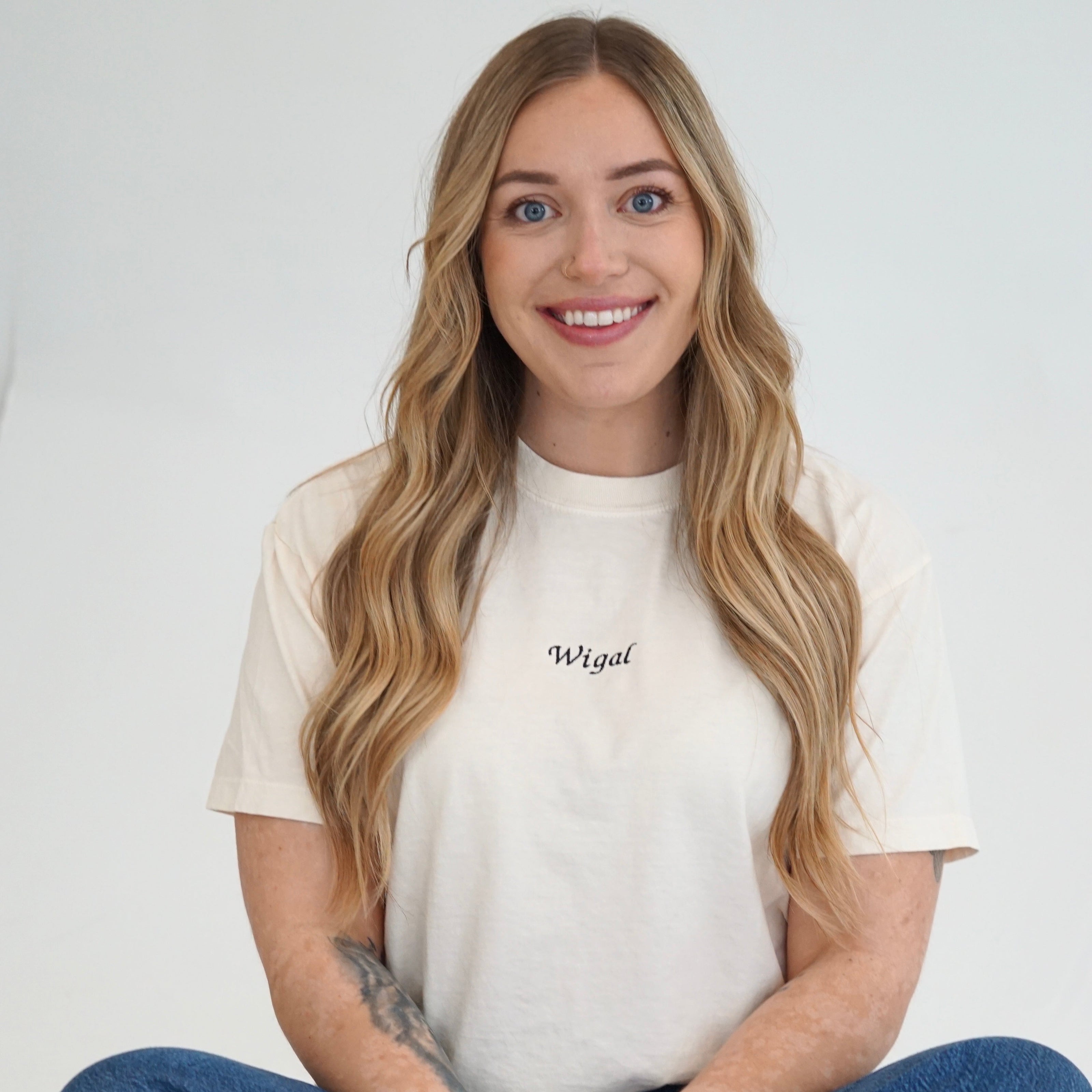Woman wearing an ivory Fiancé embroidered boxy T-shirt styled with denim jeans.