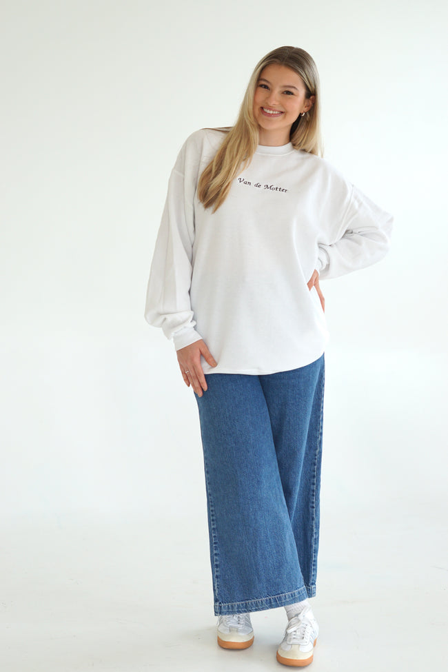 Model wearing a white embroidered bridal crewneck customized with a future last name and styled with blue jeans.