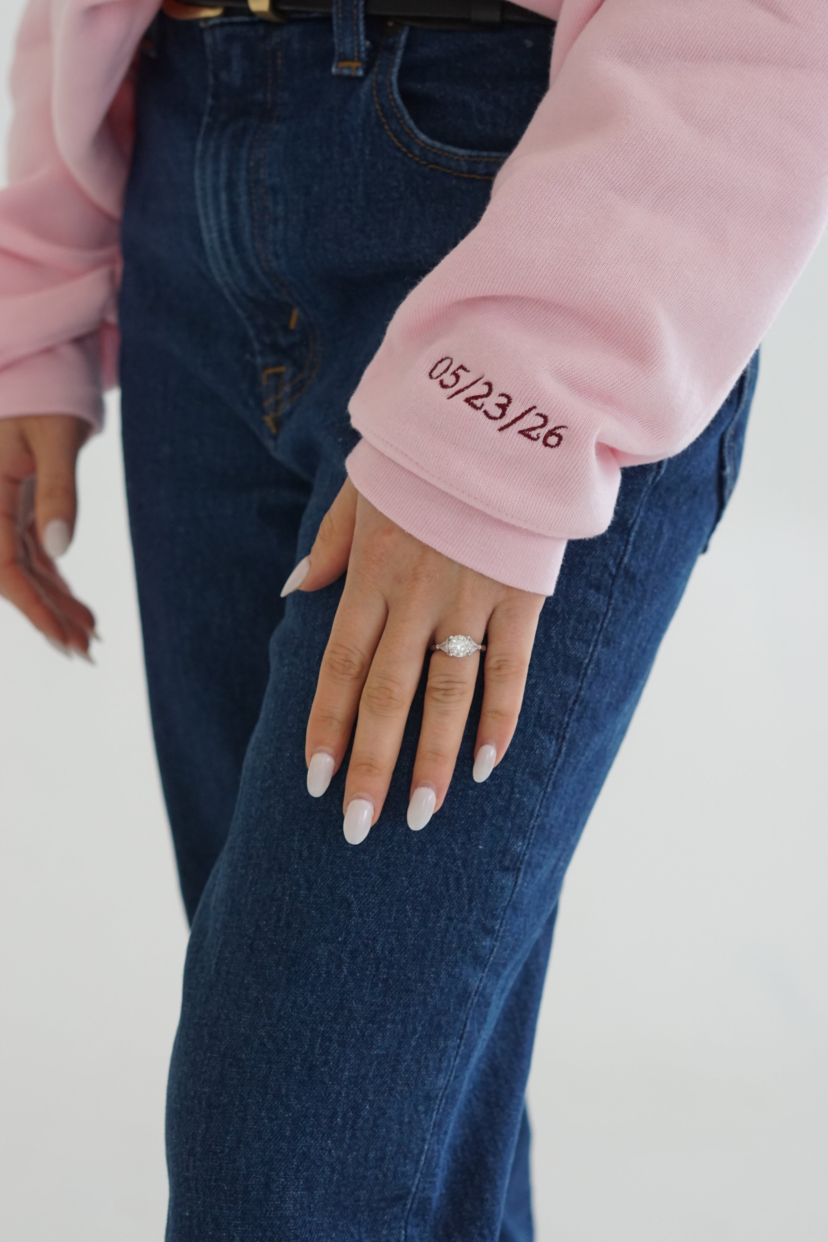 Close-up of custom wedding date embroidery on the sleeve of a personalized bridal crewneck sweatshirt.