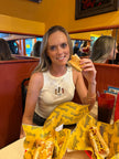 Model wearing the Glizzy Season embroidered tank while enjoying hot dogs at a restaurant.