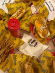 Flat lay of the Glizzy Season embroidered tank surrounded by hot dogs, fries, and classic diner food.