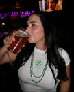 Woman wearing a white fitted baby tee with green embroidered four-leaf clover design.