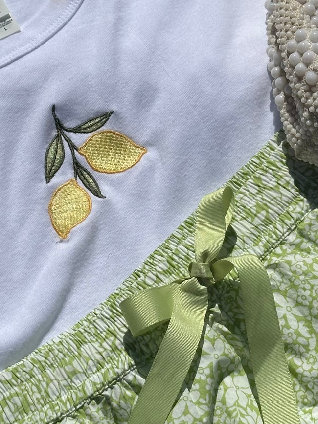 Flat lay of the Lemon Embroidered Baby Tee styled with green floral shorts and a beaded handbag.