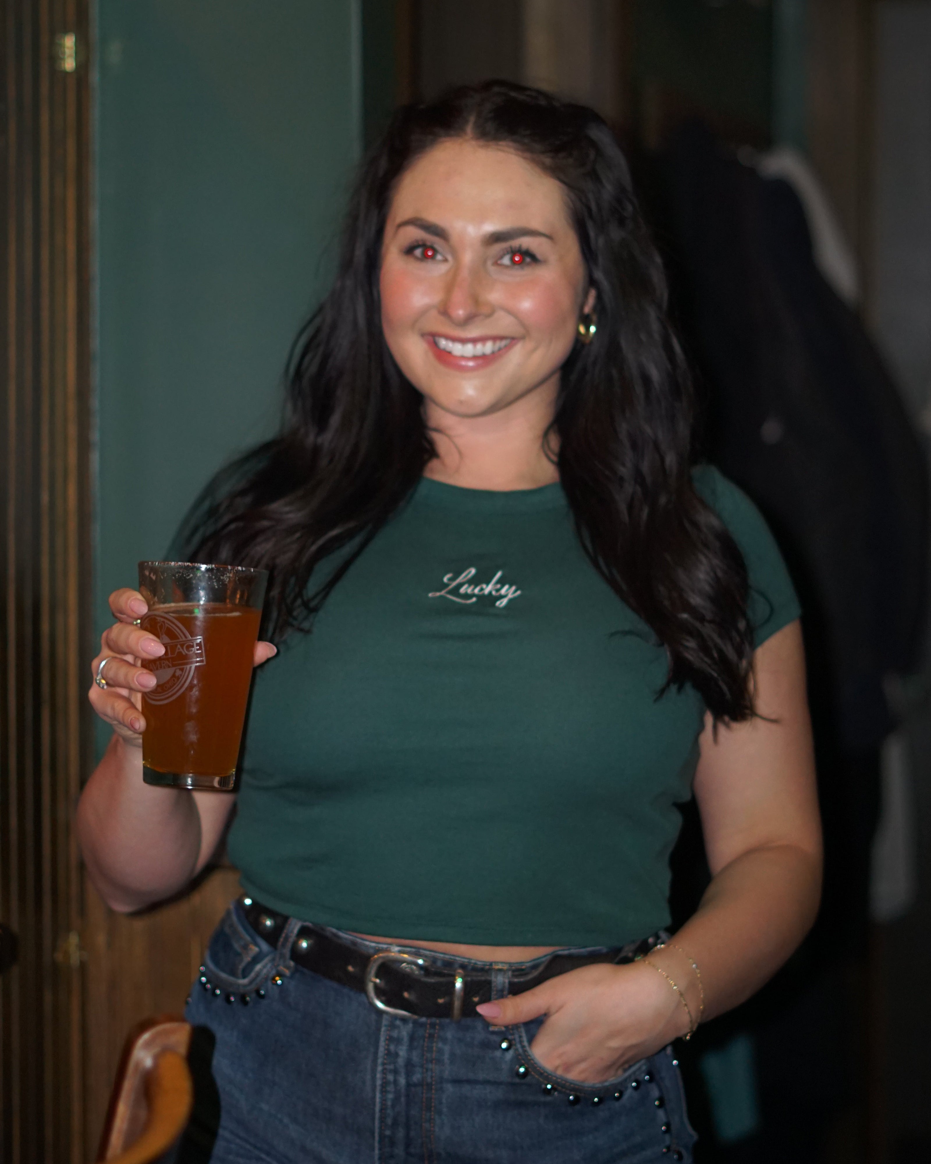 Woman wearing a forest green baby tee embroidered with white 