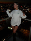 Woman wearing a cream crewneck with green embroidered “Lucky” lettering, styled for a St. Patrick’s Day.