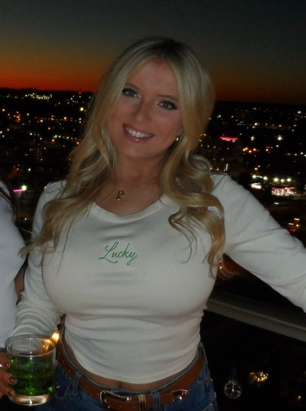 Woman wearing an ivory long sleeve baby tee embroidered with green 