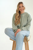 Model wearing a sage green personalized Mama embroidered crewneck sweatshirt with light wash jeans.