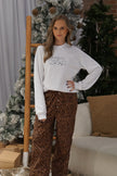Model styling a white holiday crewneck sweatshirt with an embroidered New York City-inspired Christmas scene.