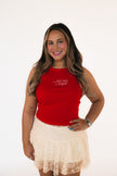 Woman wearing a red tank top with text and a beige lace skirt on a white background