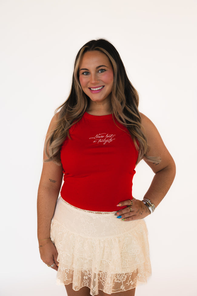 Woman wearing a red tank top with text and a beige lace skirt on a white background