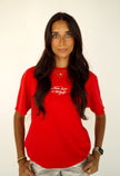 Woman wearing a red Never Lost a Tailgate embroidered, game day T-shirt.