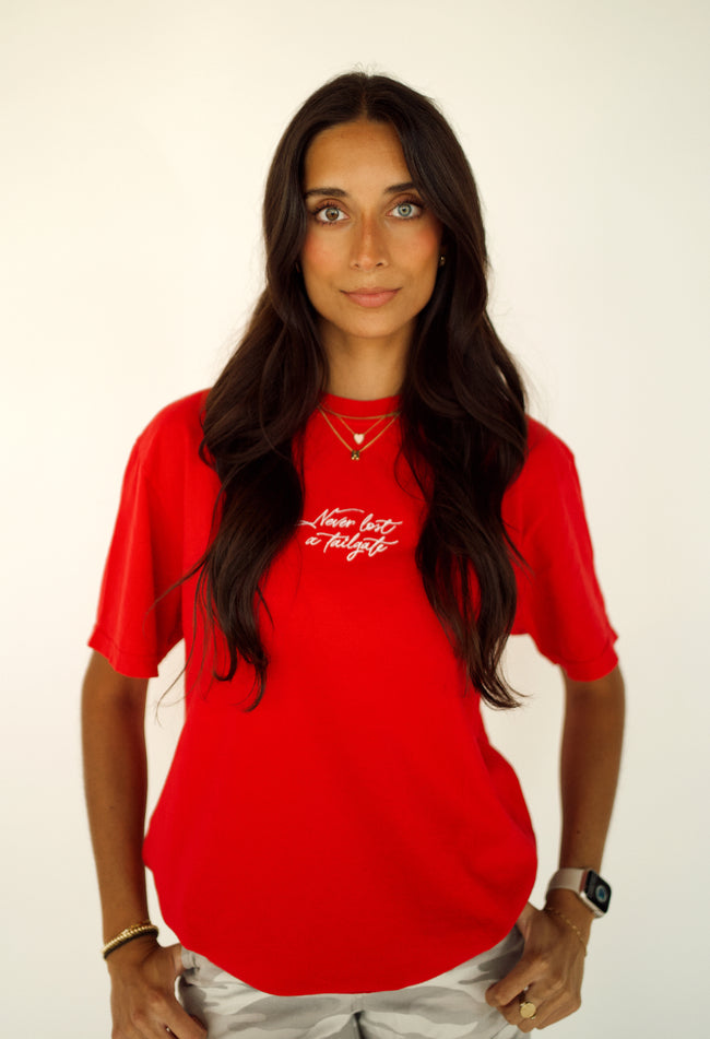 Woman wearing a red Never Lost a Tailgate embroidered, game day T-shirt.
