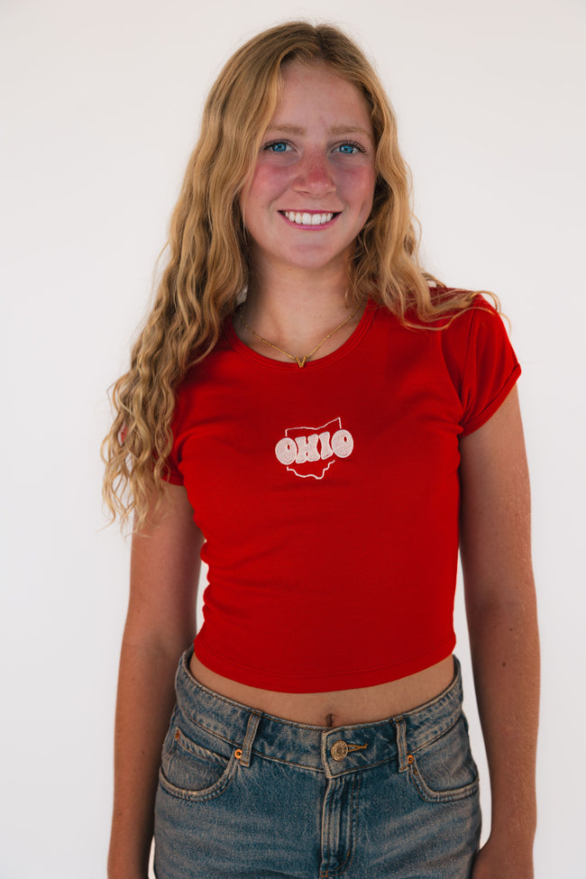 Woman wearing a fitted baby tee embroidered with the outline of the state of Ohio.